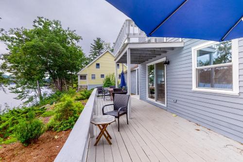 a wooden deck with chairs and a blue umbrella at Sunrise Bay in Alton Bay