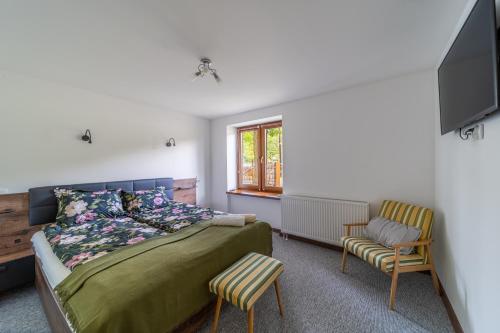a bedroom with a bed and a tv and a chair at Pod Śnieżnymi Kotłami in Piechowice