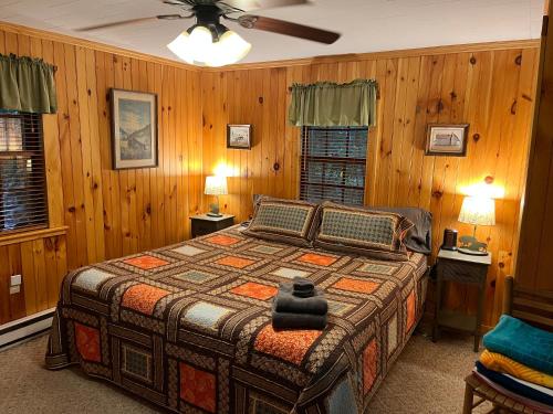 Schlafzimmer mit einem Bett mit Holzwänden und einer Decke in der Unterkunft Cozy Cabin Pet Friendly ADA Compatible in Maggie Valley