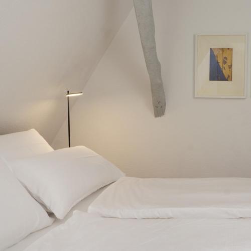 a white bedroom with two white beds and a lamp at bellasBnB an der Jagst in Möckmühl