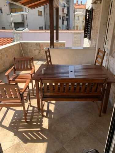 een houten tafel en 2 stoelen op een patio bij Apartman Belamaric in Šibenik