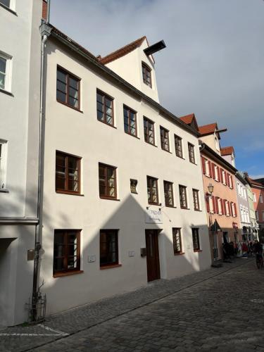a large white building on a cobblestone street at Das Fischer Boardinghouse KF in Kaufbeuren