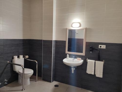 La salle de bains est pourvue d'un lavabo, de toilettes et d'un miroir. dans l'établissement Hotel Novo, à Ponferrada