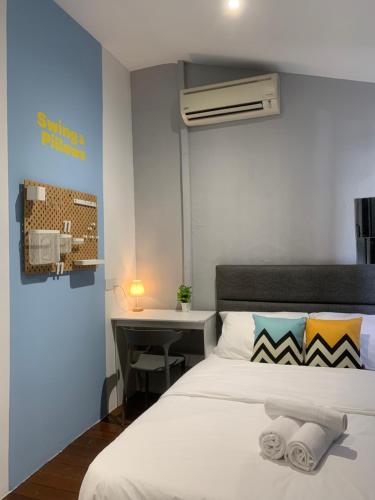 a bedroom with a bed and a desk with a laptop at Swing & Pillows @ Beach Street in George Town