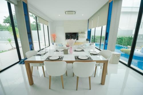 a dining room with a table and white chairs at Movenpick Pool Villa by Hello Pattaya in Na Jomtien