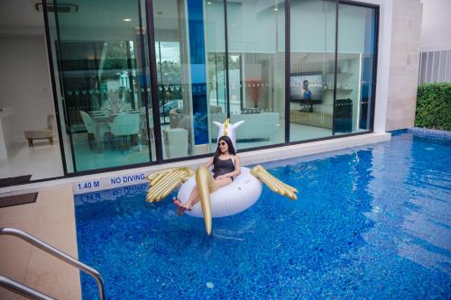 a woman sitting in an inflatable pool with a mermaid at Movenpick Pool Villa by Hello Pattaya in Na Jomtien