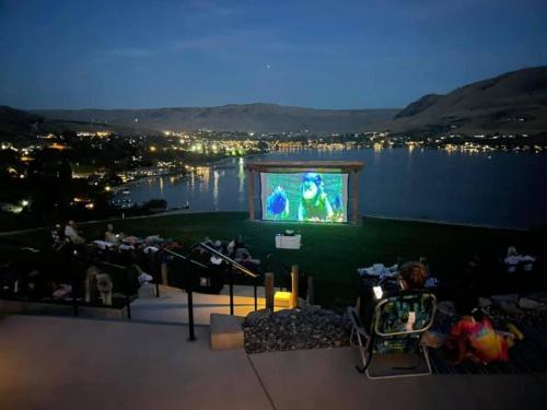 a large screen with a person on a stage with a movie at 5 O’Clock Somewhere #113 in Chelan