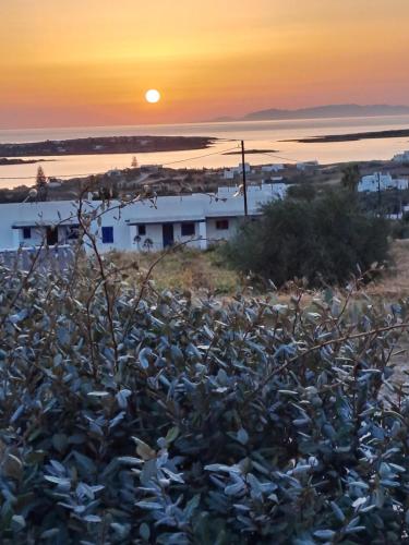 a sunset over the water with a house in the foreground at Traditional house paros in Sarakíniko