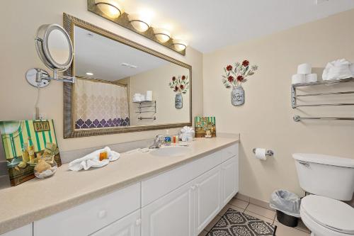 a bathroom with a sink and a mirror and a toilet at Sunshine Beach Condo with Balcony Pool Hot Tub in Daytona Beach