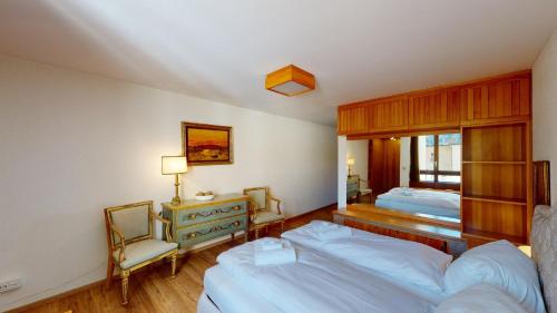 1 dormitorio con 2 camas, escritorio y espejo en St. Moritzerhof 51, en St. Moritz