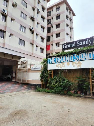 un grand bâtiment avec un panneau indiquant le grand hôtel de sable dans l'établissement Hotel The Grand Sandy, à Cox's Bazar
