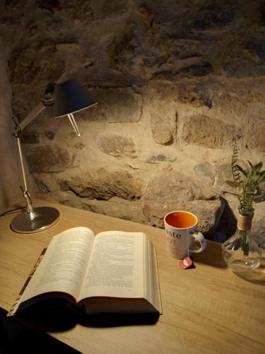 an open book on a desk with a lamp and a cup of coffee at Casa rural El Forn d'Alcudia de Veo in Alcudia de Veo