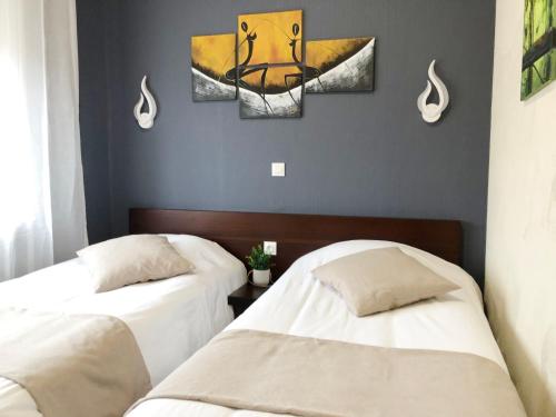 a room with two beds and a painting on the wall at L'EMBLEME - BOUTIQUE HOTEL in Beaurepaire