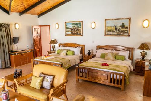 a bedroom with two beds and a couch and a chair at Villa Caballero in Au Cap