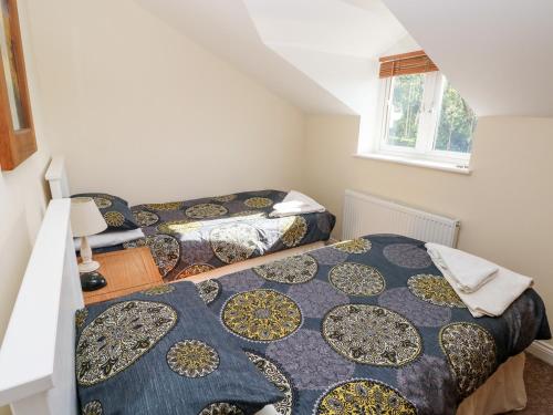 a bedroom with two beds and a window at Saddlers Cottage, Berllandeg Farm in Clynderwen