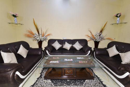 a living room with two leather couches and a coffee table at Hotel Sai Sham in Amritsar