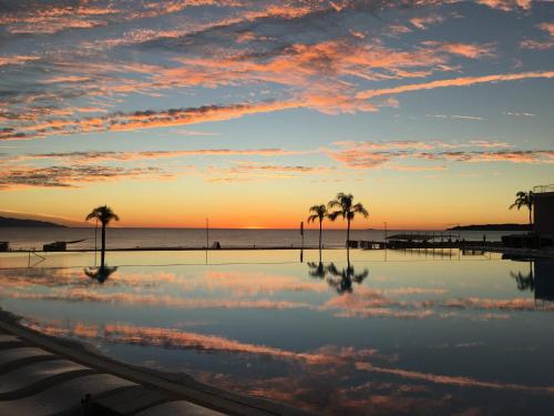 a pool with palm trees and the ocean at sunset at Estudio 573 Nuevo Vallarta, frente al mar, equipado y amueblado ! in Nuevo Vallarta