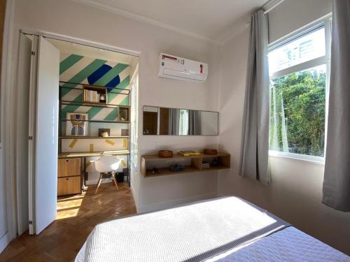 a bedroom with a bed and a desk and a window at Elegância à Beira-Mar: Apto 1Qto c/ Smart TV in Rio de Janeiro
