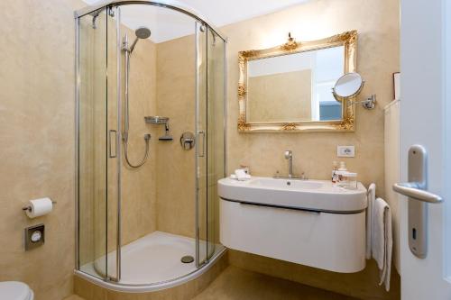uma casa de banho com um chuveiro, um lavatório e um espelho. em Appartement im Grünweinhof em Montagna