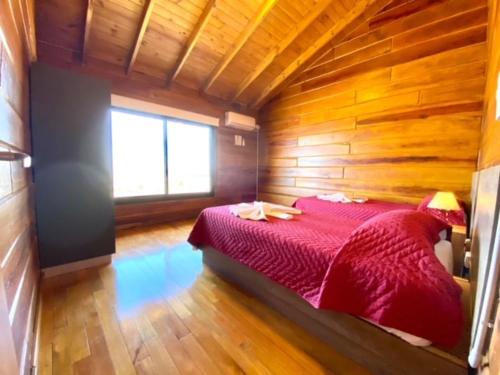 a bedroom with a red bed in a wooden room at Alma Serrana - Suites de montaña! in La Cumbrecita