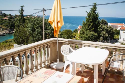 a balcony with a white table and an umbrella at Apartments Klara in Utjeha