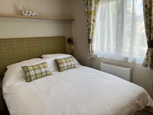 1 dormitorio con 1 cama blanca y 2 almohadas en 3 Bedroom Caravan MC34, Lower Hyde, Shanklin, Isle of Wight, en Shanklin