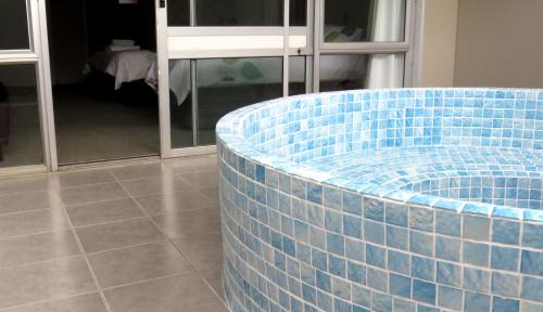 Habitación con bañera de azulejos azules en el medio de una habitación en Kuirau Park Motor Lodge, en Rotorua