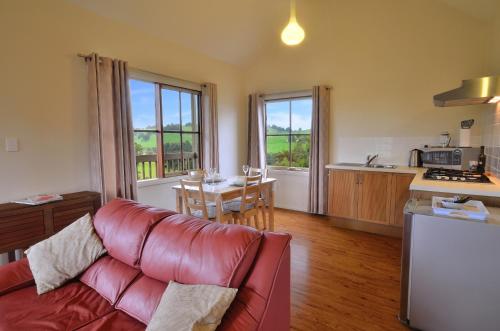 a living room with a red couch and a kitchen at Balingup Highview Chalets in Balingup