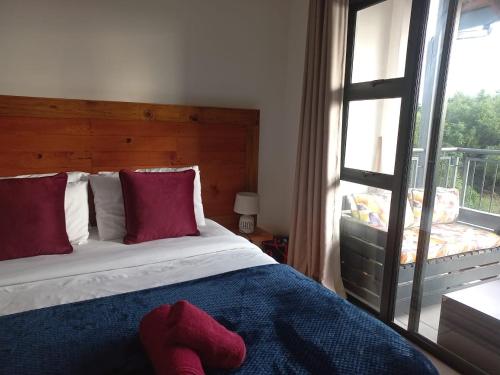 a bedroom with a bed with red pillows and a window at The Blyde Modern Oasis Pretoria in Pretoria