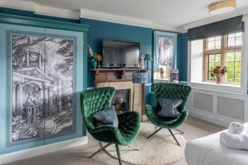 a living room with two green chairs and a fireplace at The Dial House in Bourton on the Water