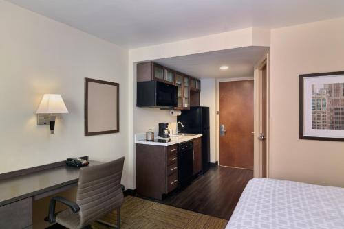 a hotel room with a bed and a desk and a kitchen at Candlewood Suites NYC -Times Square by IHG in New York