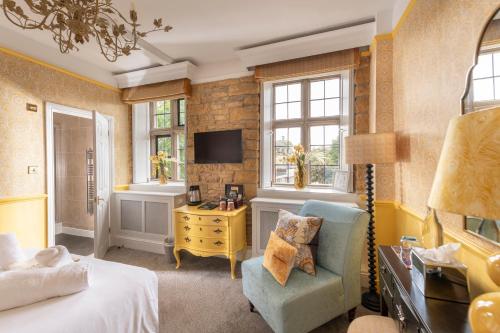 a bedroom with a bed and a chair and a tv at The Dial House in Bourton on the Water