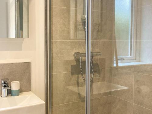 a shower with a glass door next to a sink at Sonas in Torlundy