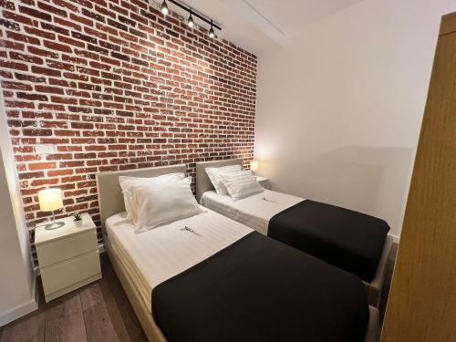 two beds in a room with a brick wall at Casa Armeana Studios in Iaşi