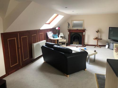 a living room with a black couch and a fireplace at Executive Serviced Apartments 3 in Forfar