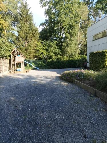 a driveway with a house and a playground at Woning gelegen in rustige bosrijke omgeving in Wingene