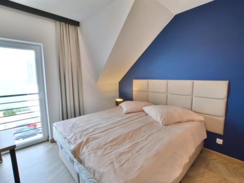 - une chambre avec un grand lit et un mur bleu dans l'établissement Comfortable apartment right by the sea, Ustronie Morskie, à Ustronie Morskie