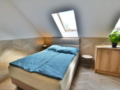 1 dormitorio con cama con sábanas azules y ventana en Comfortable apartment for 2 persons directly by the sea, Ustronie Morskie, en Ustronie Morskie