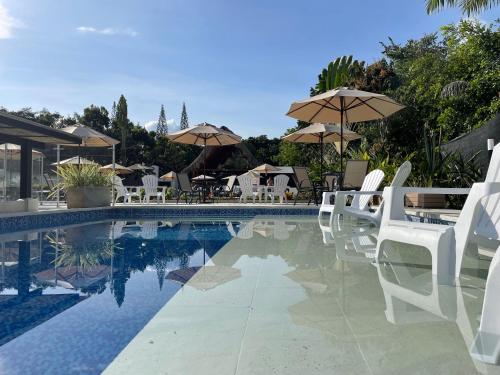 a swimming pool with white chairs and umbrellas at La Masia Hotel Boutique in Anapoima
