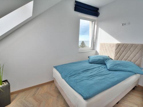 a bedroom with a bed with blue sheets and a window at Cosy apartment for 2 persons right by the sea, Ustronie Morskie in Ustronie Morskie