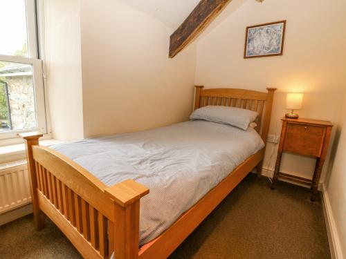 1 dormitorio con cama de madera y ventana en Tyn Llwyn, en Talsarnau