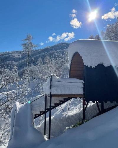 a snow covered hut with the sun in the background at Woodhide - Cottages near Batumi, Georgia in Zeda Ch'khutunet'i