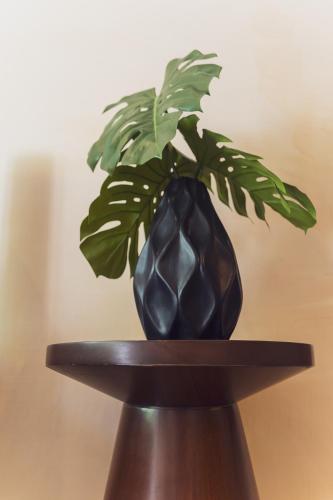 a black vase with a plant in it on a table at Stylish 2BR Apt Private Pool, Terrace, Fast WiFi Tulum A102 in Tulum