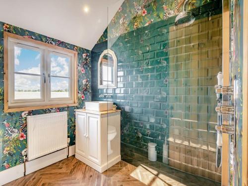 a bathroom with green tiled walls and a toilet at Stable Barn in Saint Lawrence