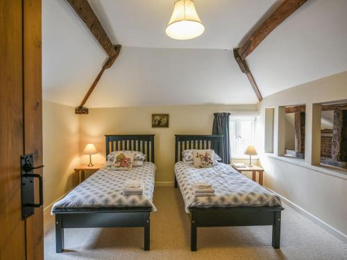 dwa łóżka w małym pokoju z dwoma lampami w obiekcie Garth Ucha w mieście Llanyblodwel