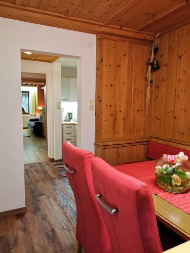 a dining room with a table and red chairs at ban Kneissl`s in Umhausen