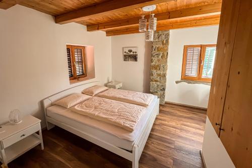 ein Schlafzimmer mit einem Bett in einem Zimmer mit Holzdecken in der Unterkunft Istrian Stone House with a big garden in Marezige