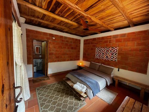 1 dormitorio con cama y pared de ladrillo en Origen Hostel en El Zaino