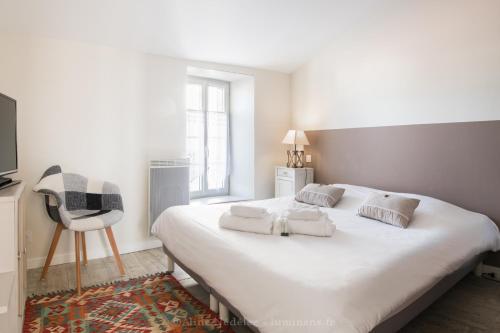 um quarto com uma grande cama branca e uma cadeira em La Virginie - Suite Ile'Ô em La Couarde-sur-Mer