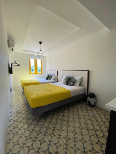 1 dormitorio con 2 camas con sábanas amarillas y ventana en Hotel Nest, en San Juan